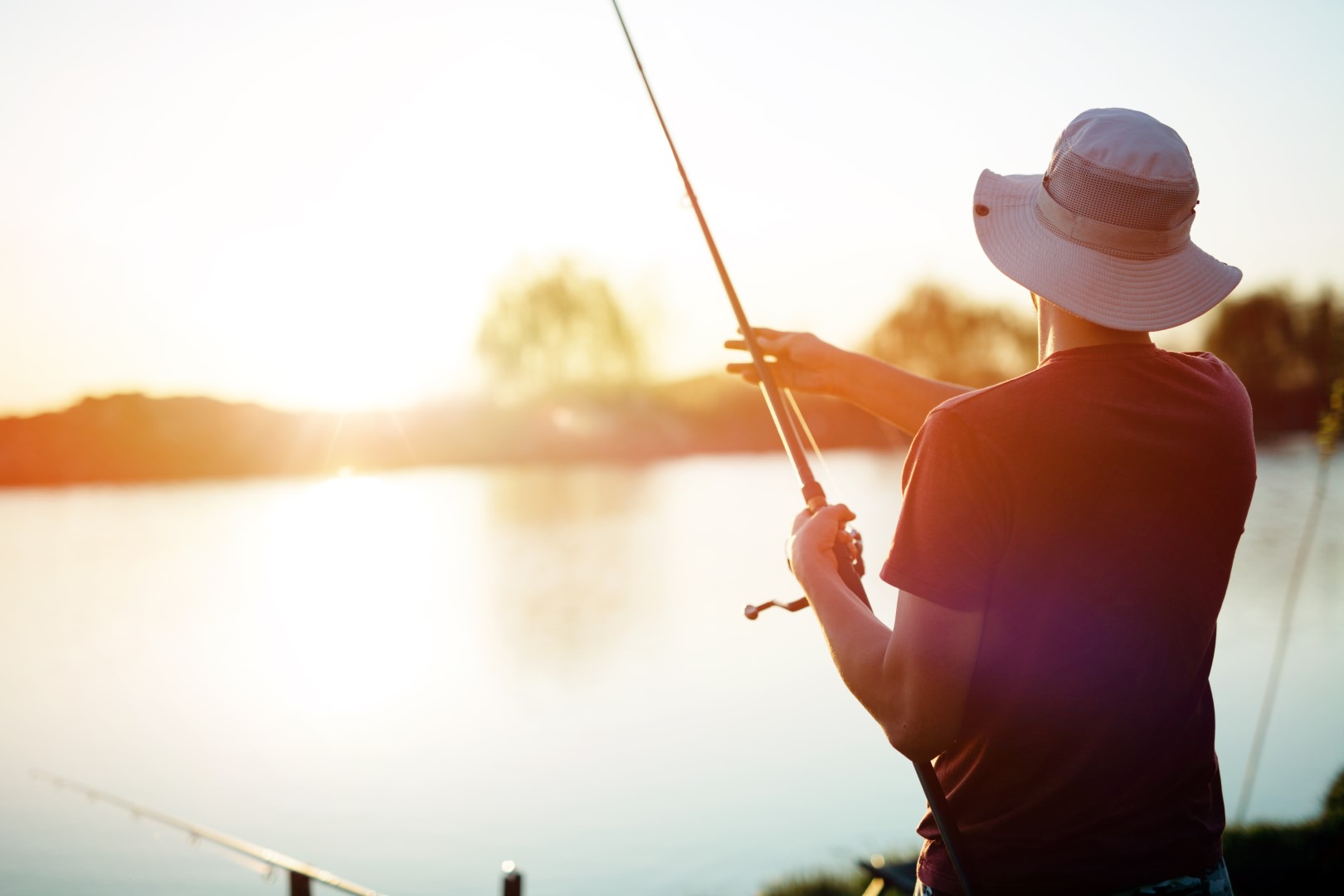 Man fishing on lake at sunset