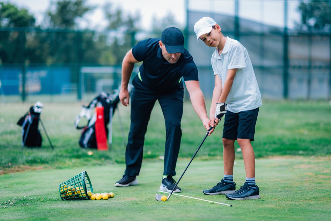 Dad teaching young son how to golf
