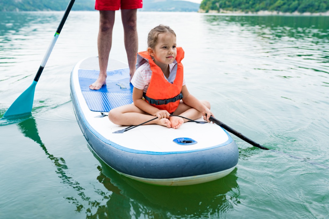Young girl sitting at the front of a paddle board